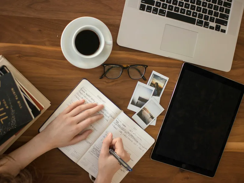 A person writing in a notebook at a desk
